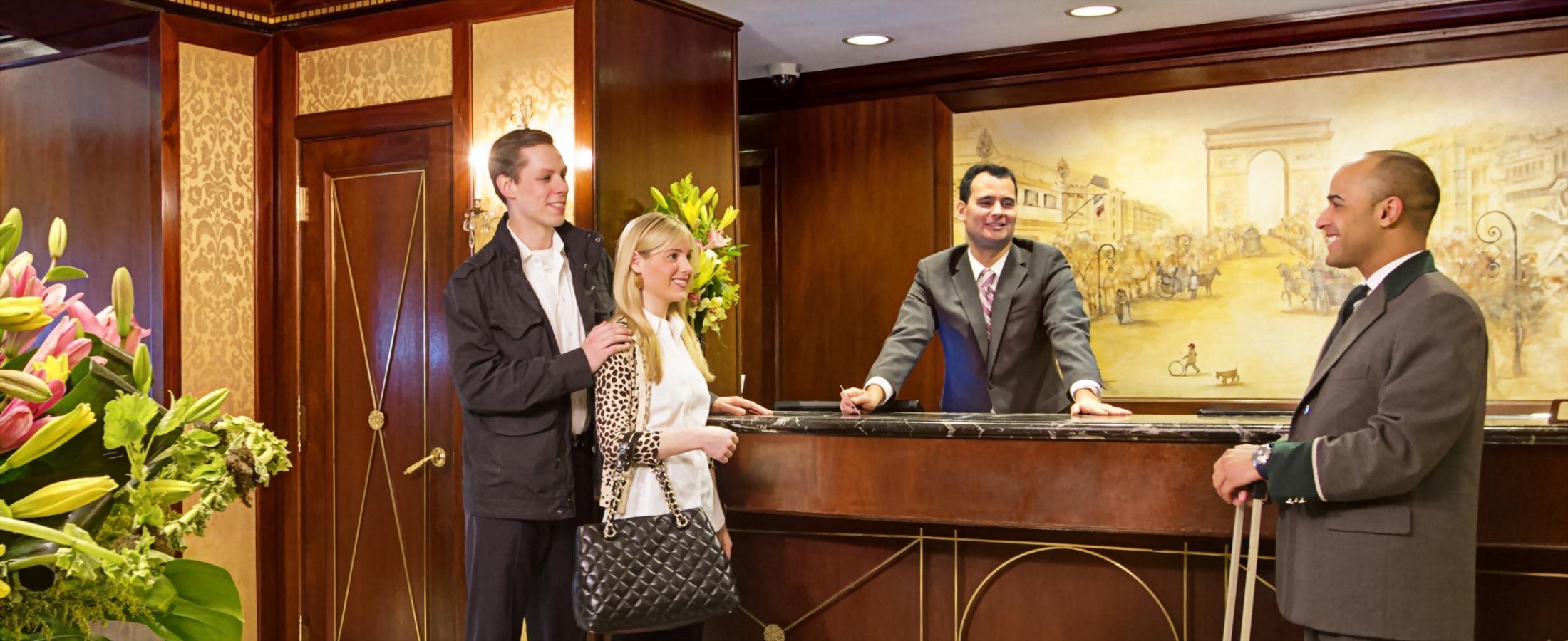 couple checking in at front desk with help from the bellman and guest service agent