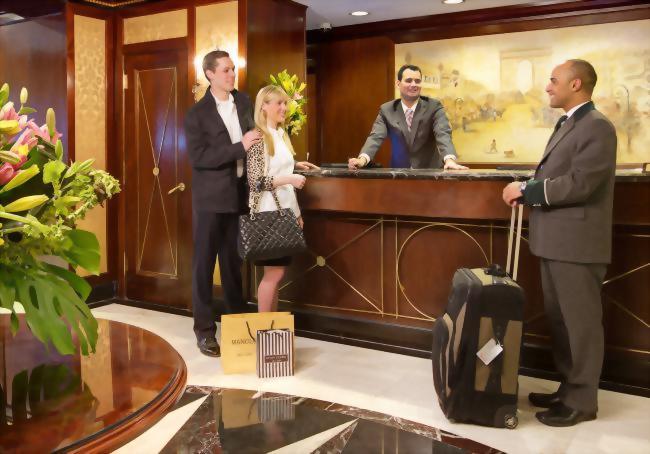 couple checking in at front desk with help of bellman